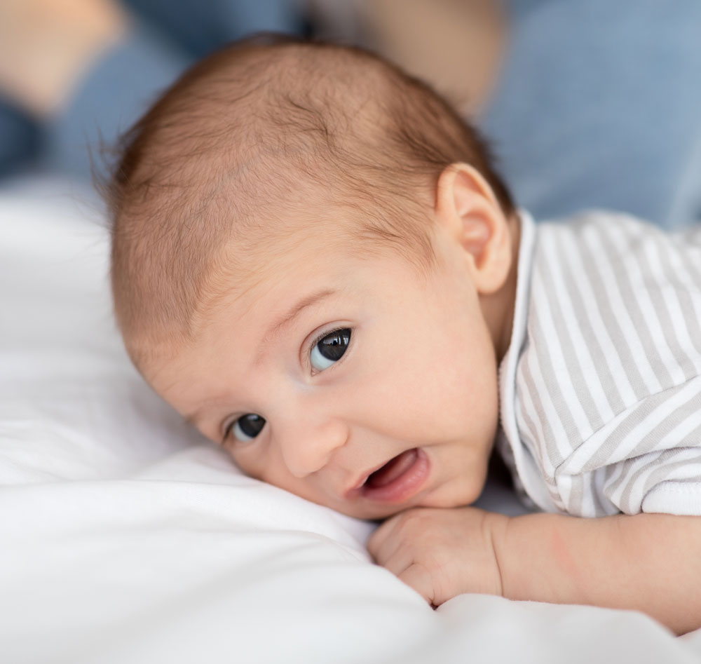Alert baby lying on tummy on bed
