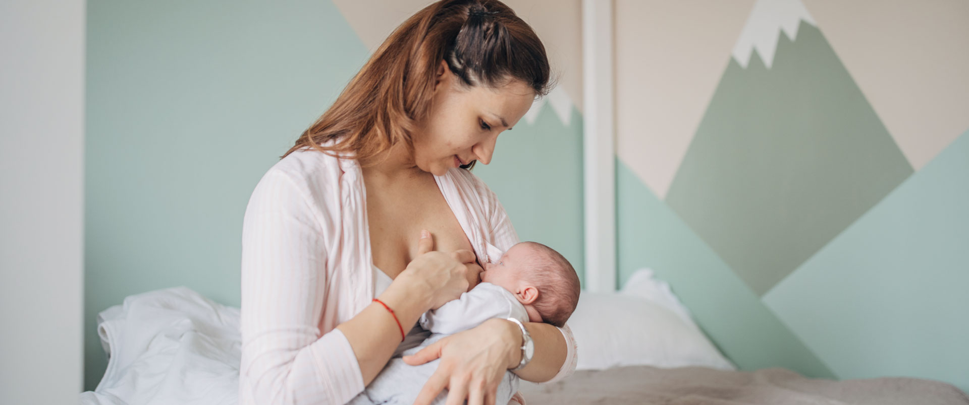 Mother breastfeeding newborn baby on bed