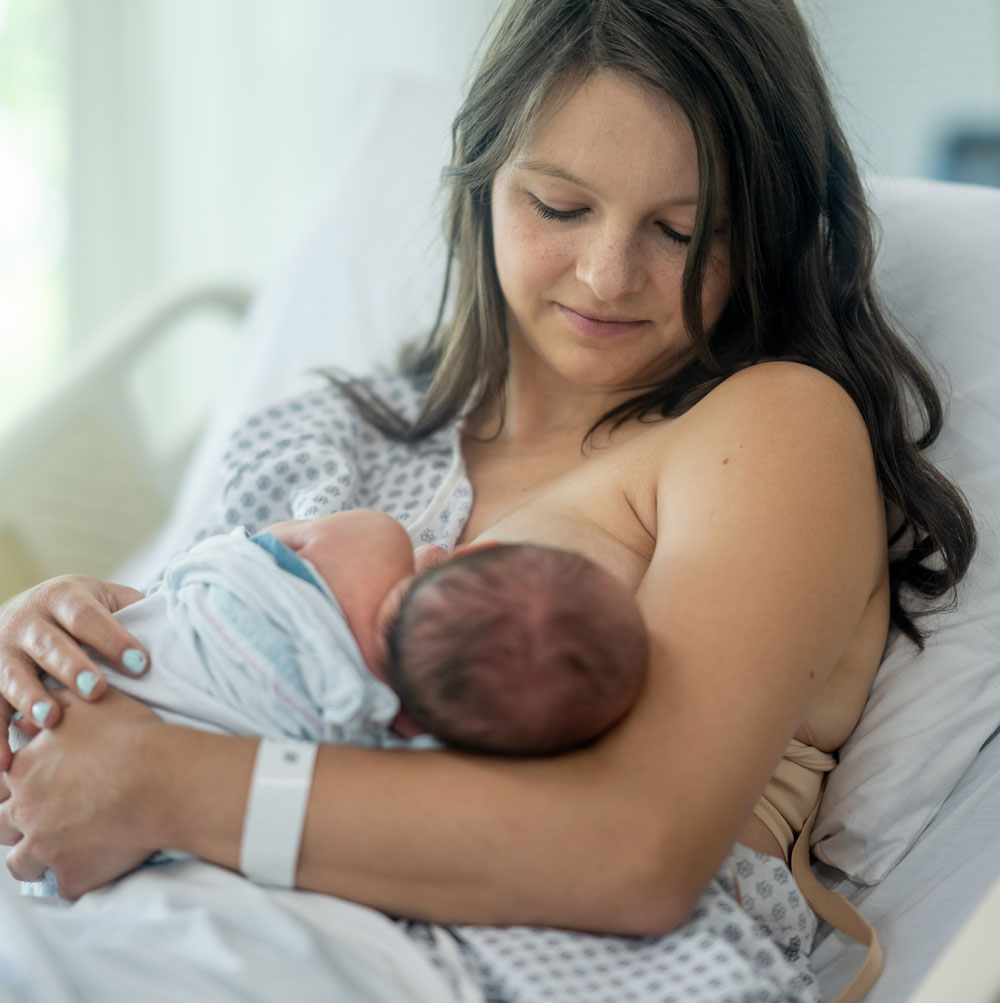 Woman nursing infant in hospital bed