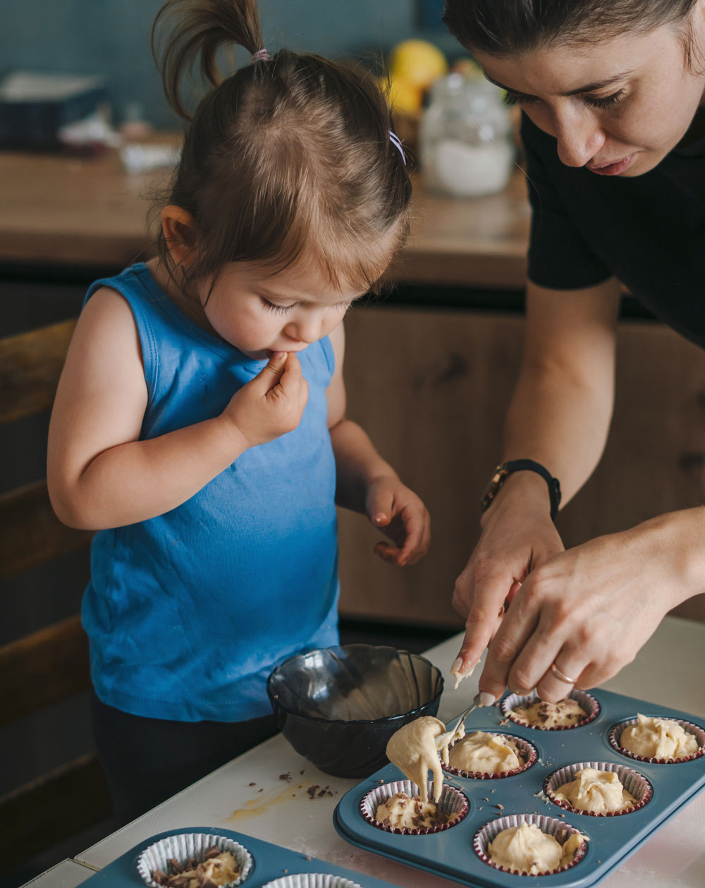 mother-spooning-batter-into-muffin-tin-with-toddler