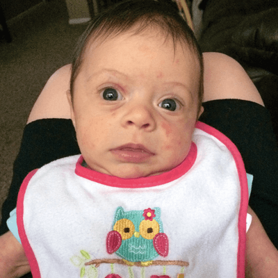Baby with bib looking curiously at camera