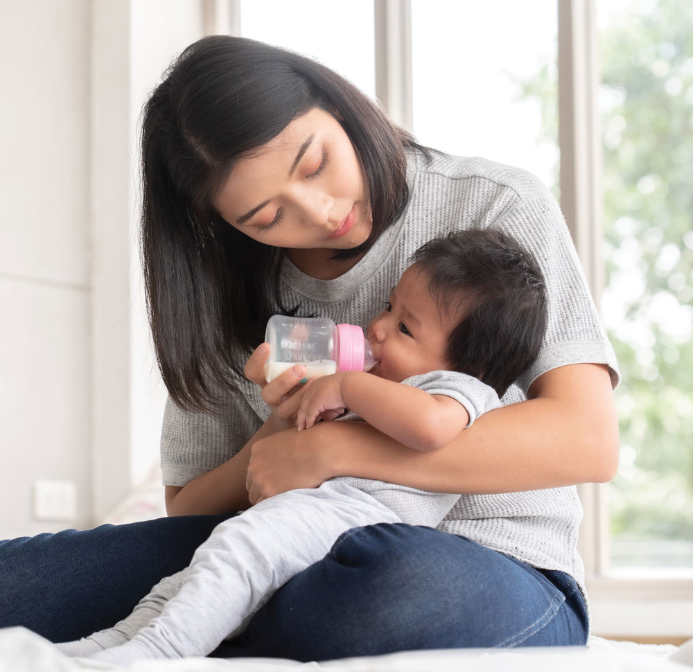 Woman feeding baby with bottle in cozy setting
