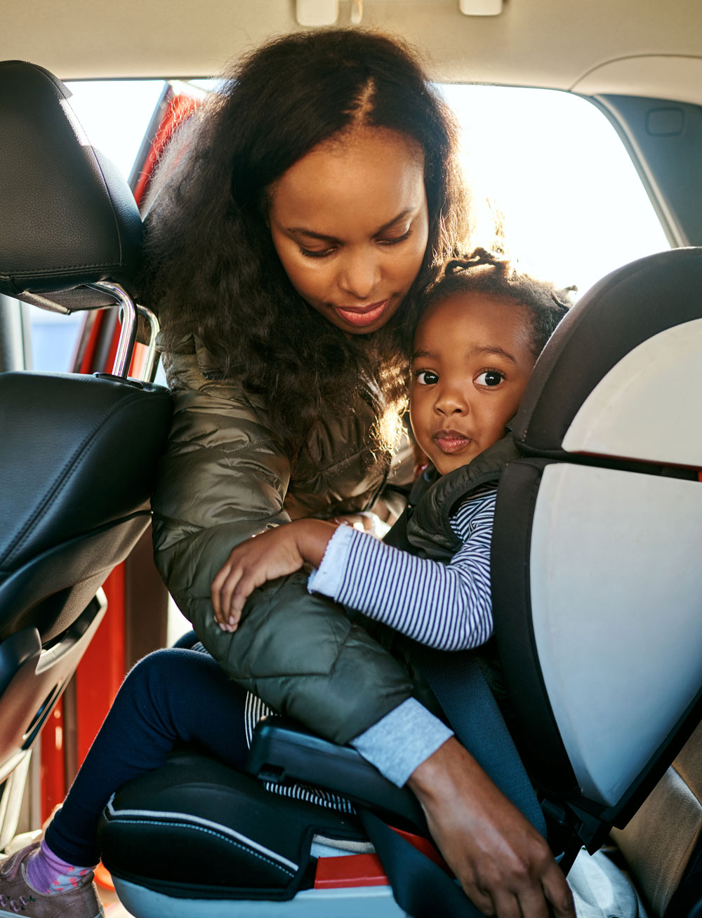 Mother securing child in car seat