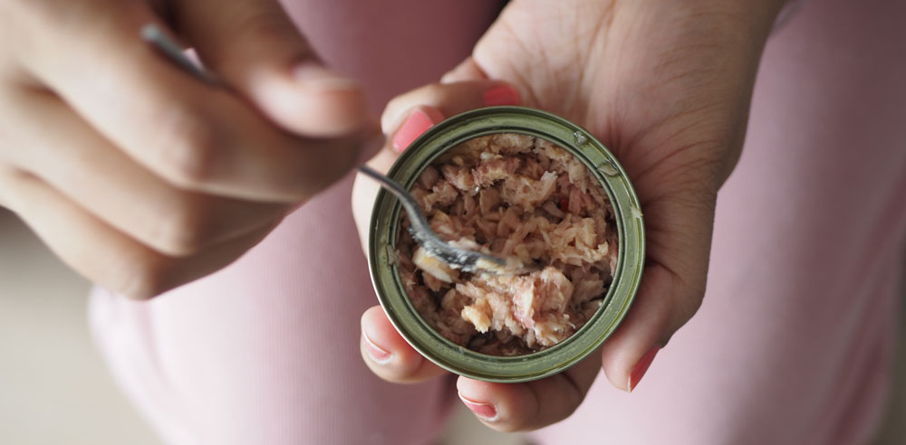 Person holding open can tuna