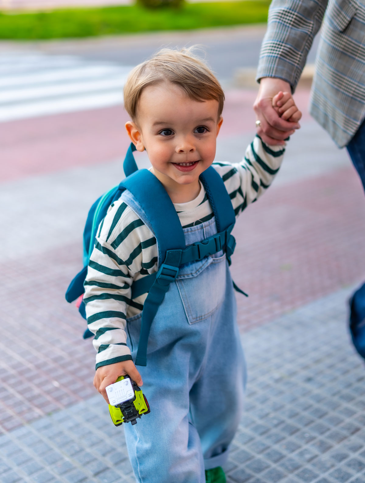 Toddler holding parents hand walking outdoors smiling