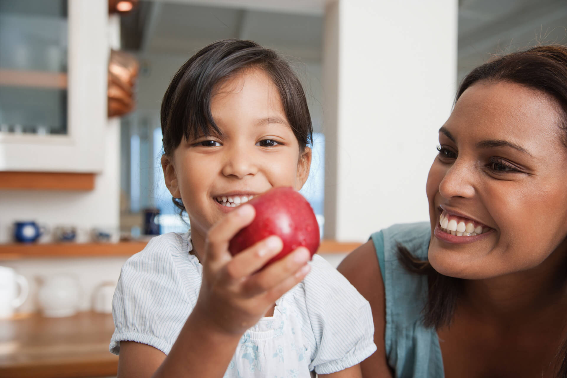 Mom Smiling at Daughter with Apple