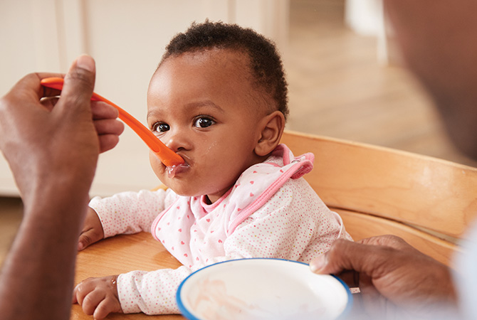 Baby being fed by parent with spoon.