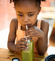 Child drinking green smoothie through a straw