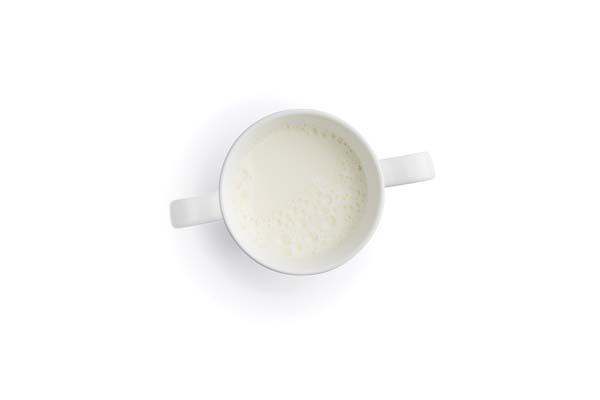 White cup filled with milk, overhead view