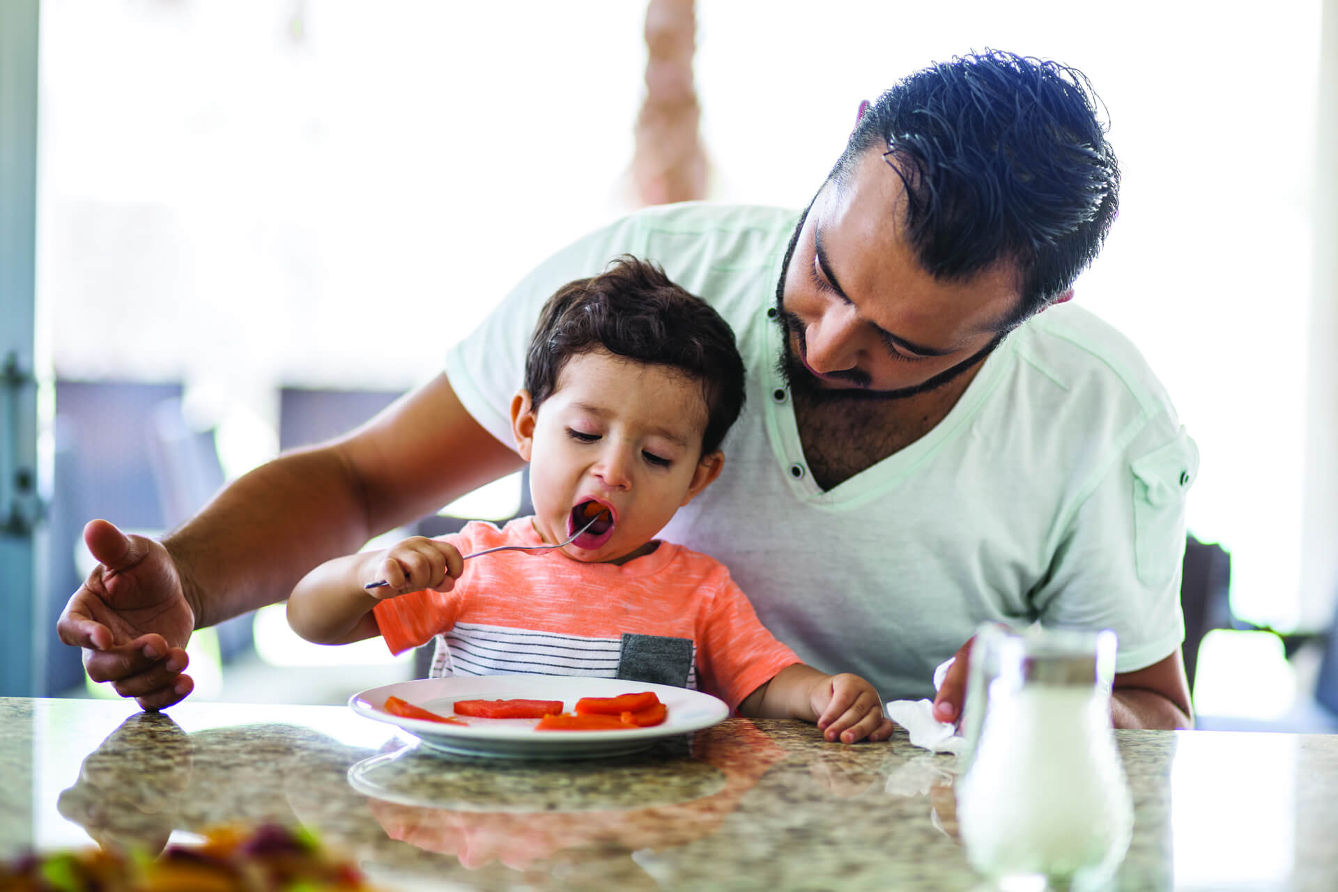 mom and toddler eating veggie smiling