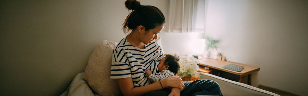 A mother in a striped shirt lovingly breastfeeds
