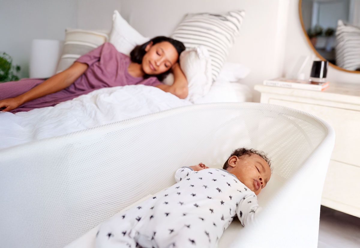 Baby sleeping in bedside bassinet