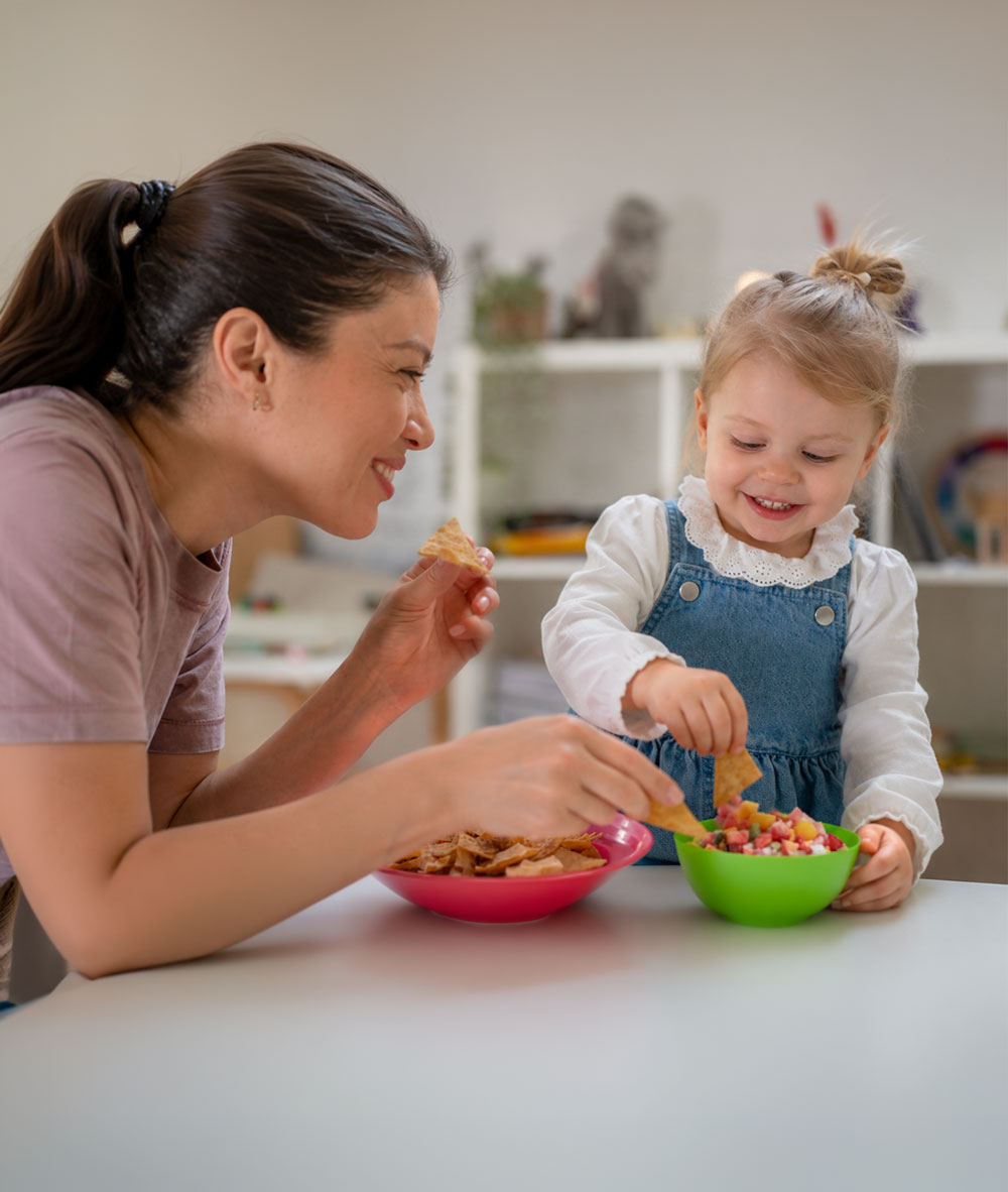 Mother and toddler sharing chips and fruit salsa