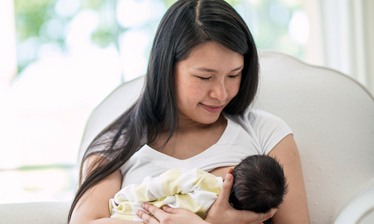 Mother holding her newborn baby at home