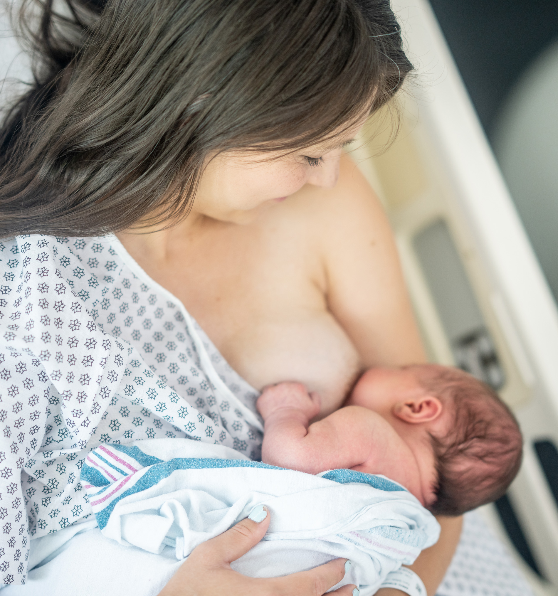 Breast feeding mother that is breastfeeding a newborn smaller baby