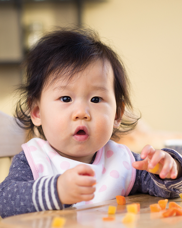 A baby wearing a bib sits at a table.