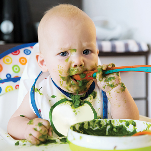 Messy baby eating greens