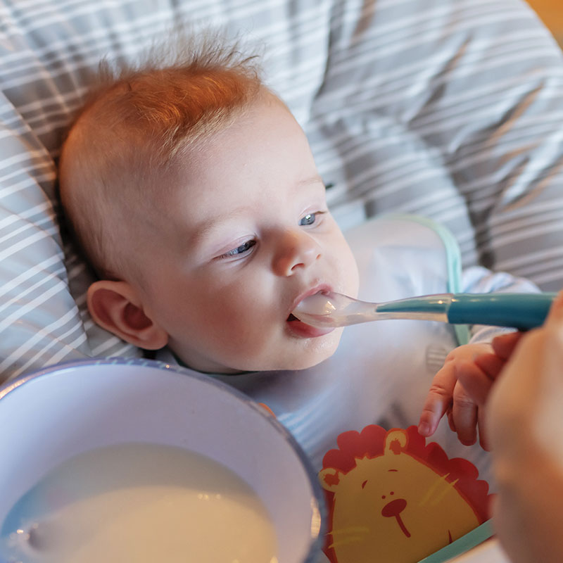 Parent feeding a baby with a spoon